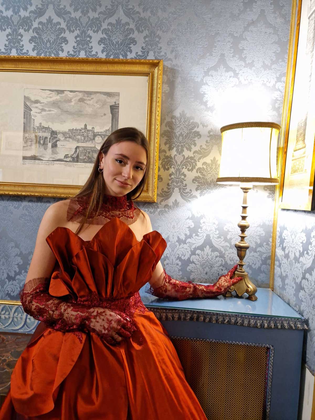 Mod’Art Roma - Il fascino dei colori - sfilata modelle nello storico Palazzo Ferrajoli - evento d’alta moda con gli eleganti abiti di Elins moda ragazza vestita in rosso bruno per matrimonio